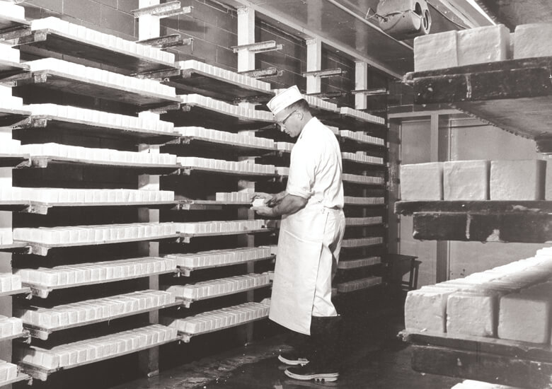 Male cheesemaker in Limburger aging room at Chalet Coop
