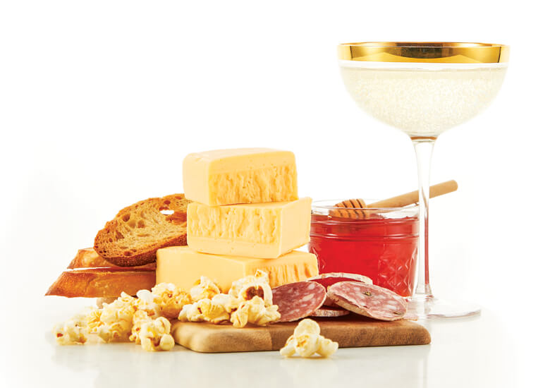 Butterkase cheese with kettle corn, honey and prosseco on plate