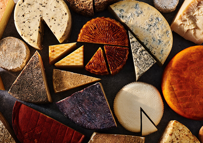Aged cheeses of varying sizes lay on a black tabletop