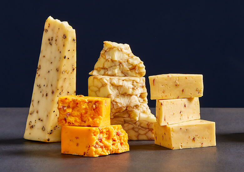 Stacks of flavored washed rind cheeses against dark blue background