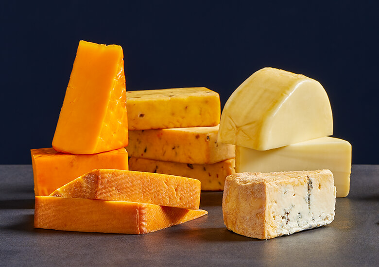 Mixed smoked rubbed cheeses against dark blue background